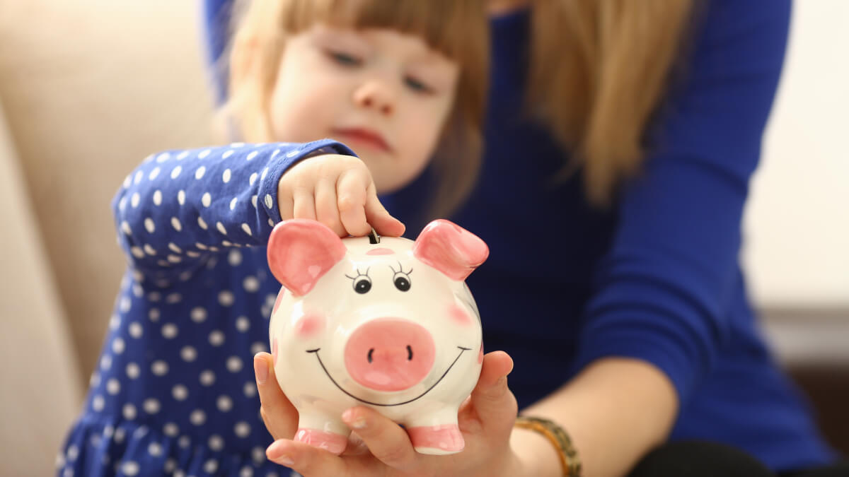 Child putting money in piggy bank